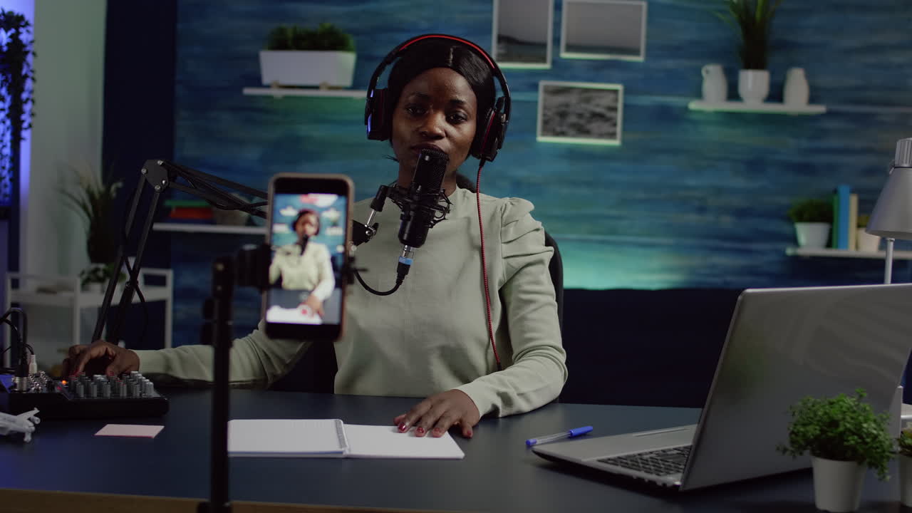 콘텐츠 제작자가 마이크에서 이야기하면서 카메라를 보고 사운드를 확인합니다.