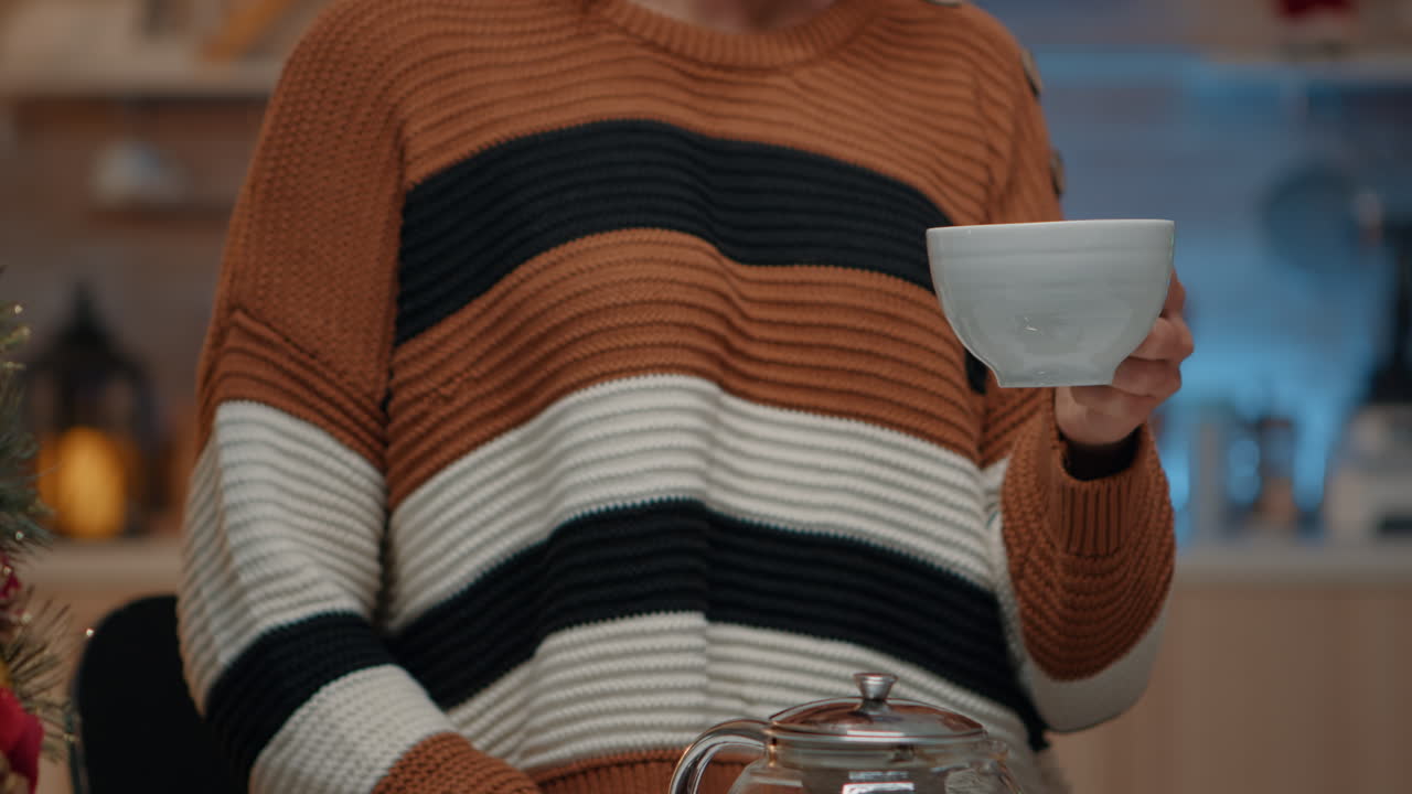 close up de un adulto joven sosteniendo una taza de té en la cocina