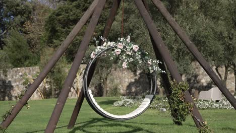 columpio circular adornado con rosas y vegetación en un marco de madera en un jardín soleado