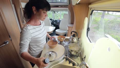 woman cooking in camper, motorhome interior