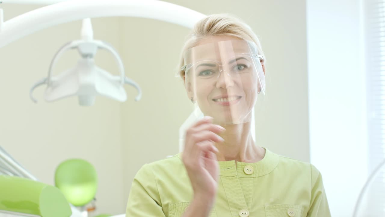 여성 치과 의사가 안전 안경을 착용하고 있습니다. 여성 의사가 일을 준비하고 있습니다.