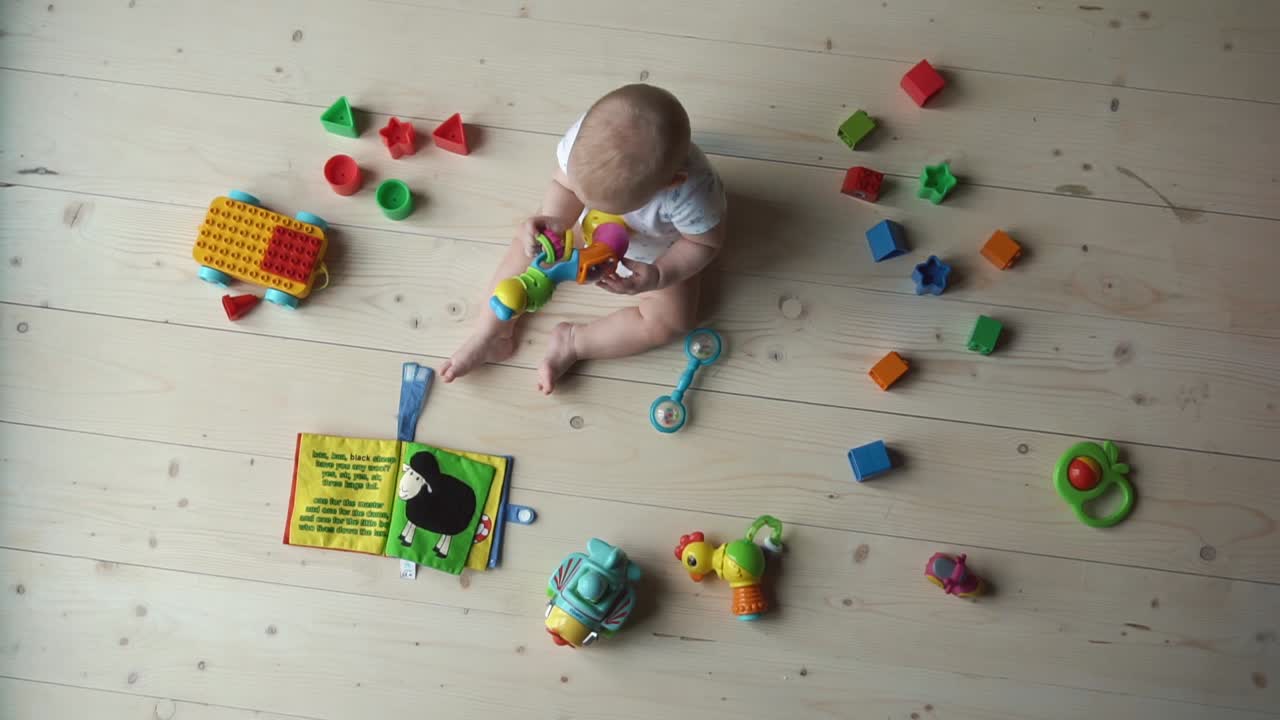 Baby playing with toys on wooden floor