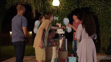 friends and family gathered for an outdoor gender reveal party at night