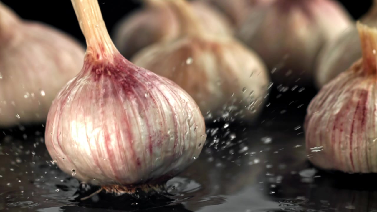 Rallentatore di un bulbo d'aglio che cade e schizza acqua