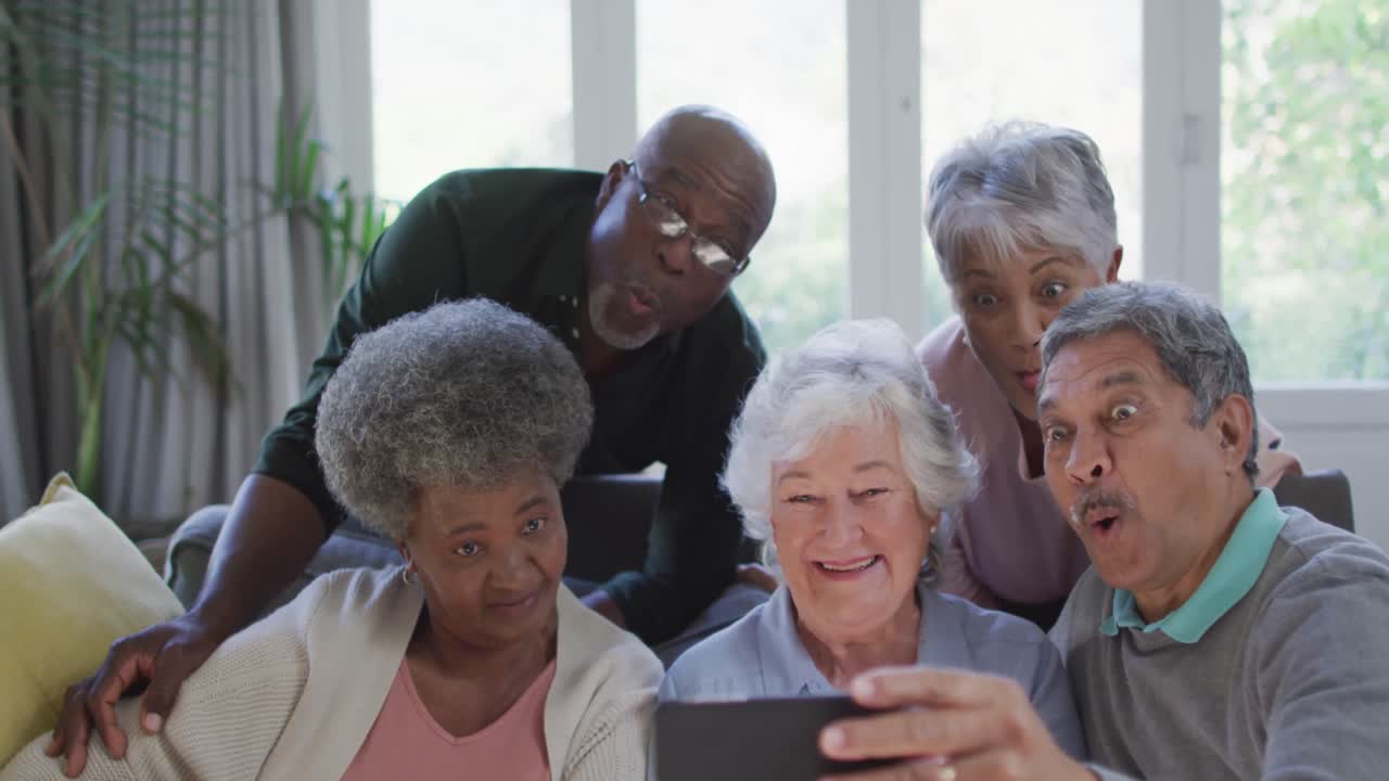 Group of diverse senior people using smartphone together at home