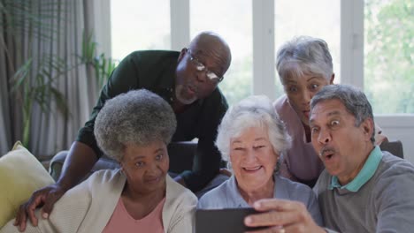 grupo de personas mayores diversas que usan teléfonos inteligentes juntos en casa