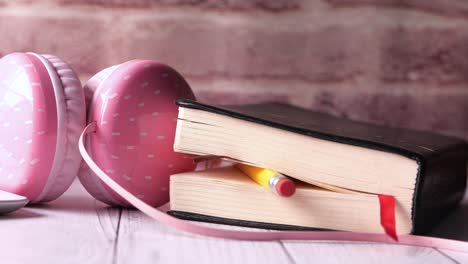 pink headphones, book, and pencil on a wooden table