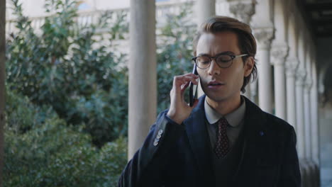 Student-talking-on-smartphone-in-colonnade-hallway.-Businessman-calling-on-phone