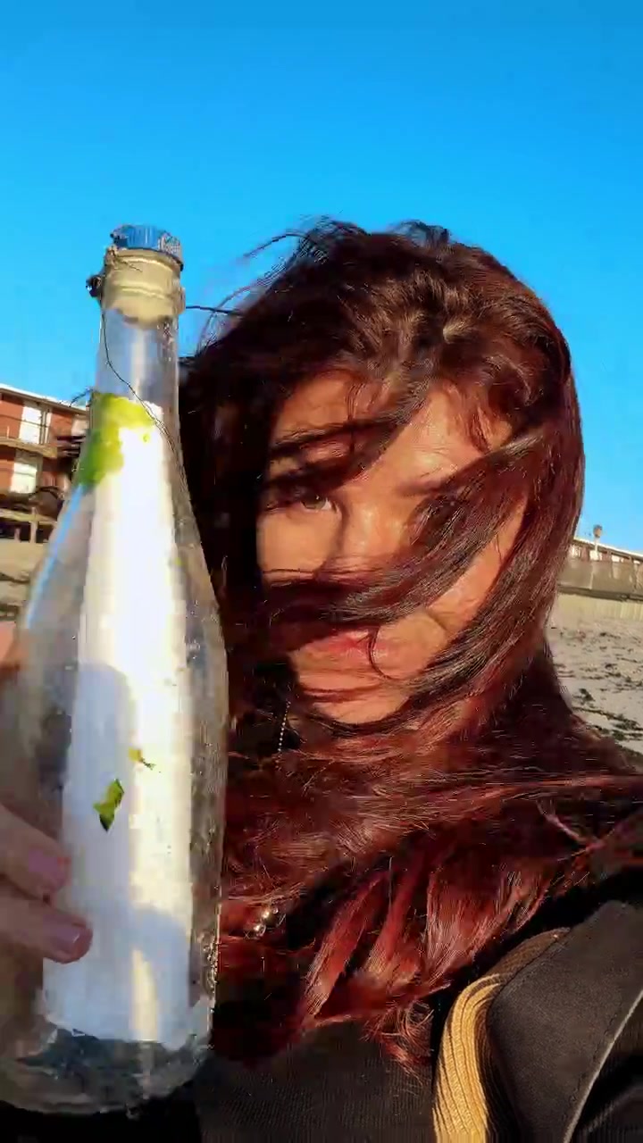 Ritratto di donna con messaggio in bottiglia. Ritratto di donna che tiene una bottiglia di vetro con un messaggio vicino alla riva dell'oceano.
