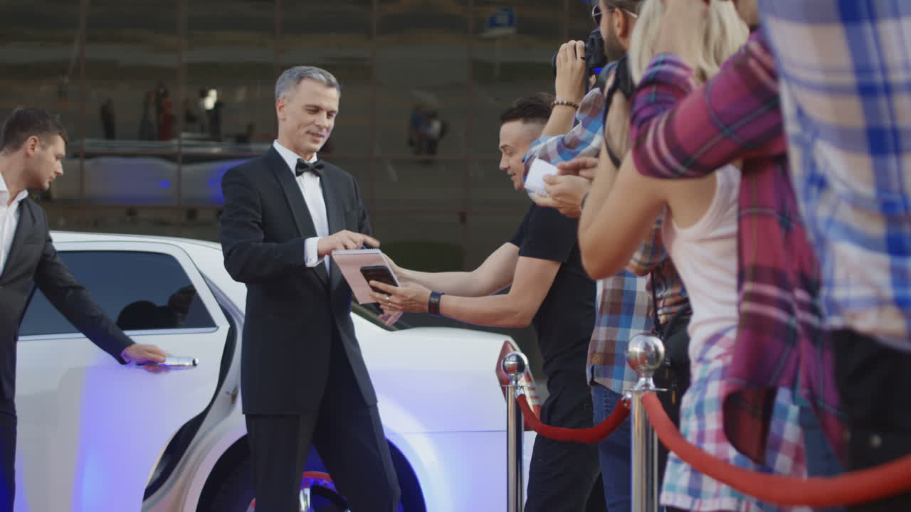 Celebrity signing autographs and interacting with fans on the red carpet