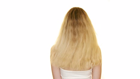 그녀의 머리를 움직이는 긴 금발 머리를 가진 날씬한 여자의 뒷면의 샷