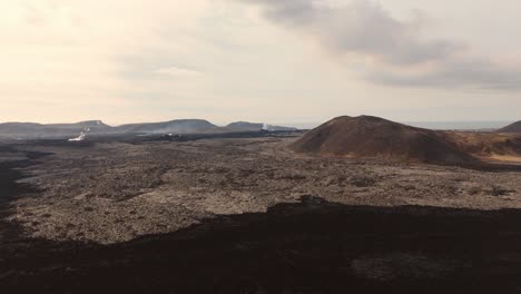 inhospitable volcanic rock landscape with smoking gas vents and mounds