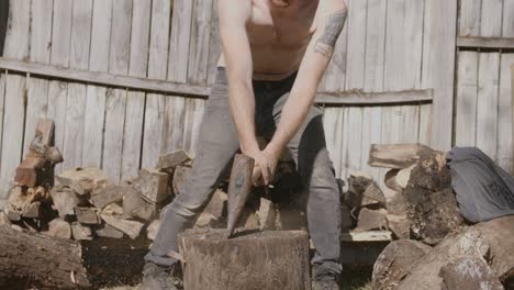 close up slow motion footage of a shirtless man splitting a log