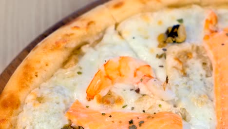 un cuarto de pizza cortada con mariscos y queso en una tabla de madera.