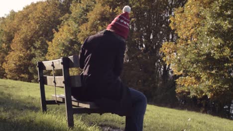 busy woman looking in bag on park bench in autumn landscape