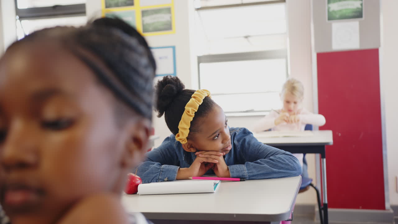 In school, girl daydreaming at desk with notebook and apple in classroom