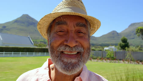 front view of senior black man looking at camera on a sunny day in back yard of home 4k