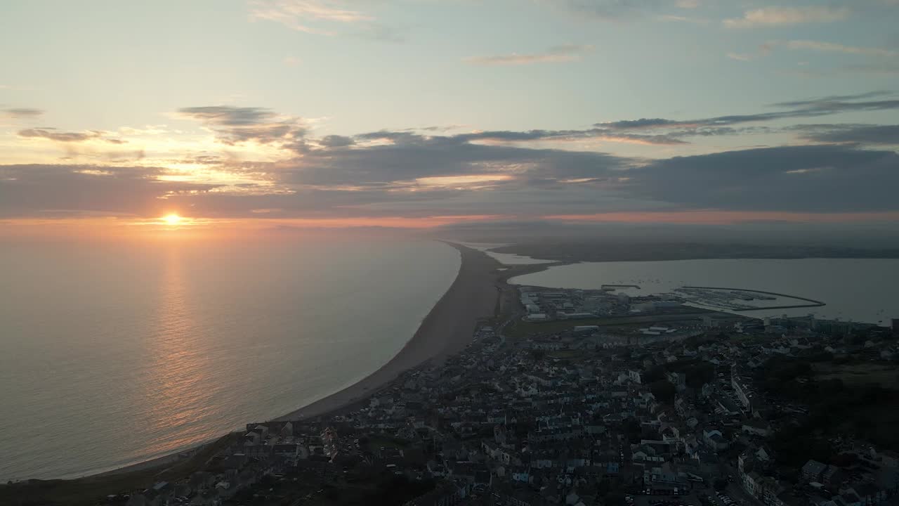 Drone flying over Chesil Beach on island of Portland, in Dorset UK, on an amazing sunset in the middle of the summer.