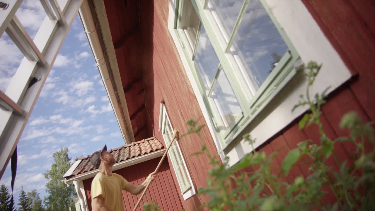 남자가 외벽에서 파루  ⁇ 은 페인트를 벗기고, 집 유지보수