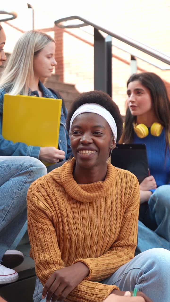 Mangfoldig gruppe unge kvindelige studerende snakker på universitetstrappen.