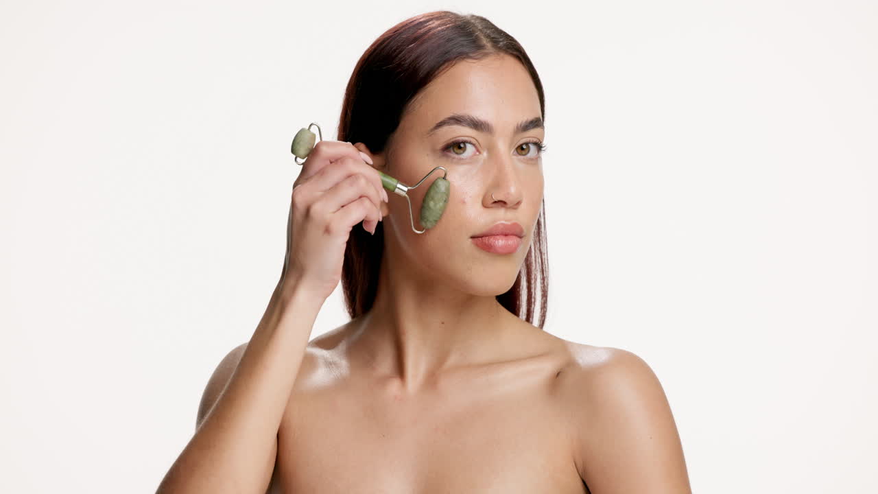 Woman using jade roller for facial massage
