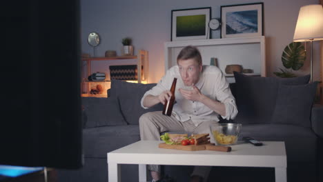 man watching tv and drinking beer at home