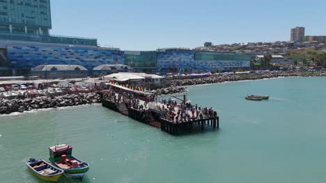 muelle con multitudes de personas cerca del puerto de san antonito en chile con muelle detrás