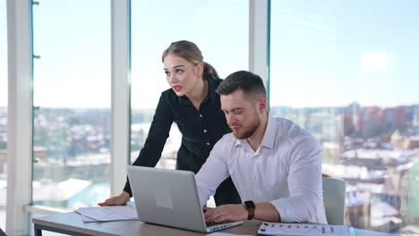 business couple work in office. beautiful woman assists handsome man sitting in front of the laptop.young entrepreneurs indoors.