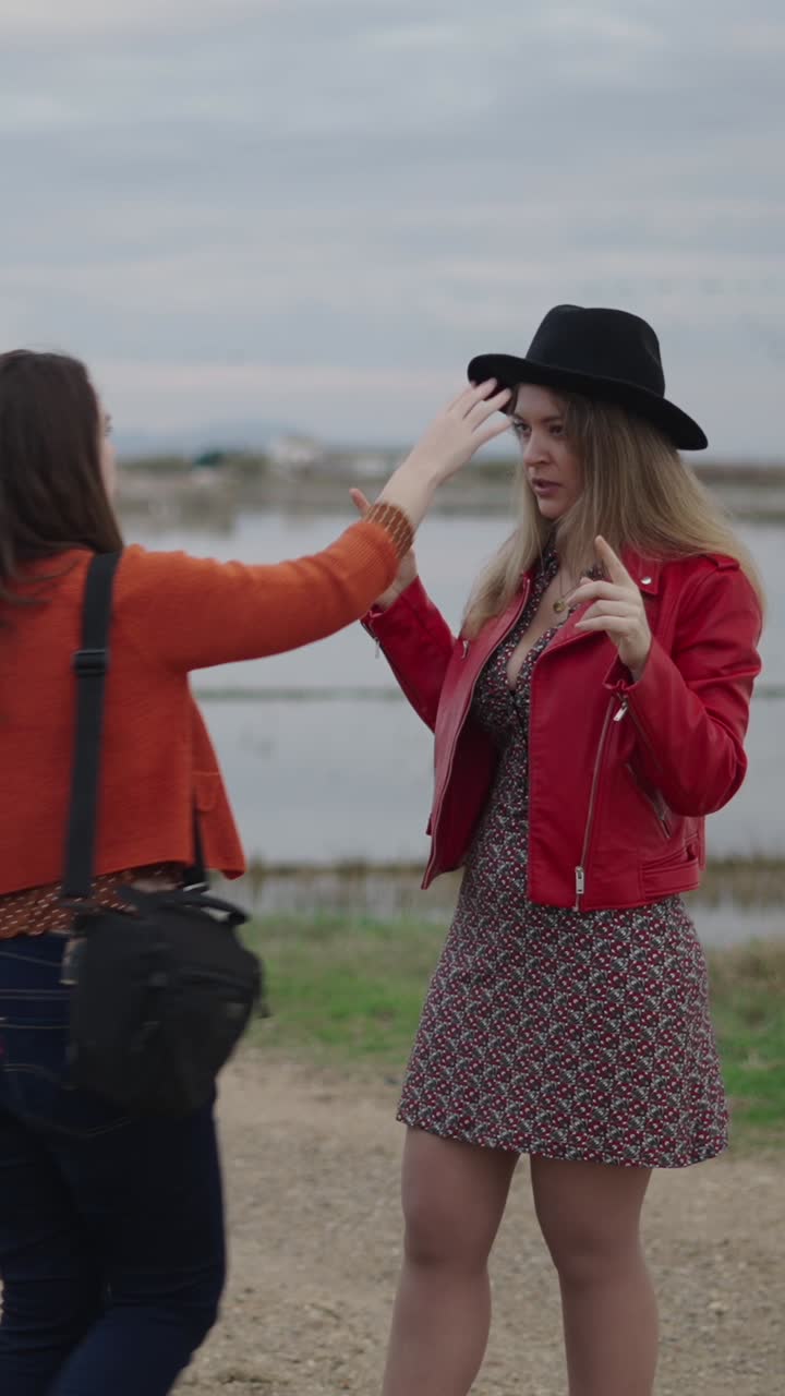 Two women outdoors, one adjusting a hat