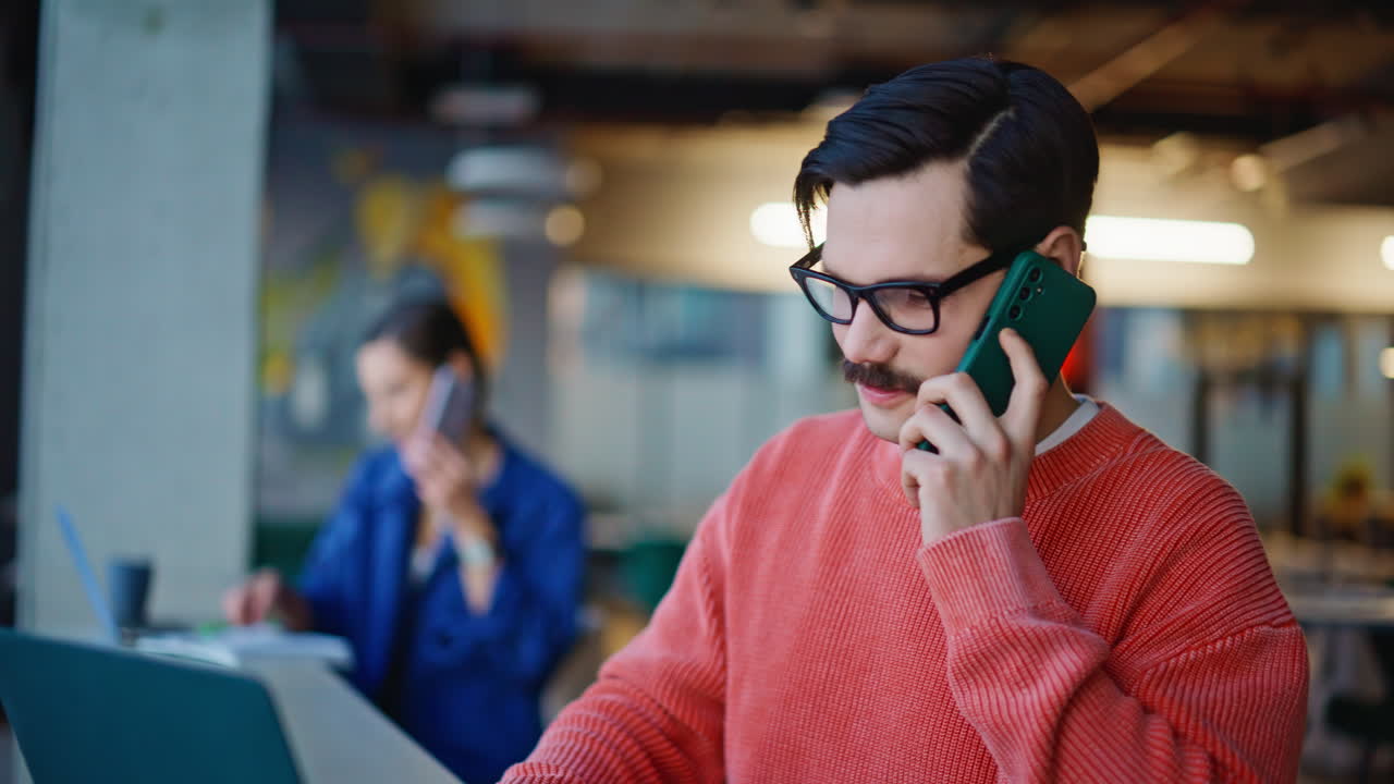 Primer plano de empleados remotos consultando su smartphone sentados en el espacio de trabajo en una cafetería
