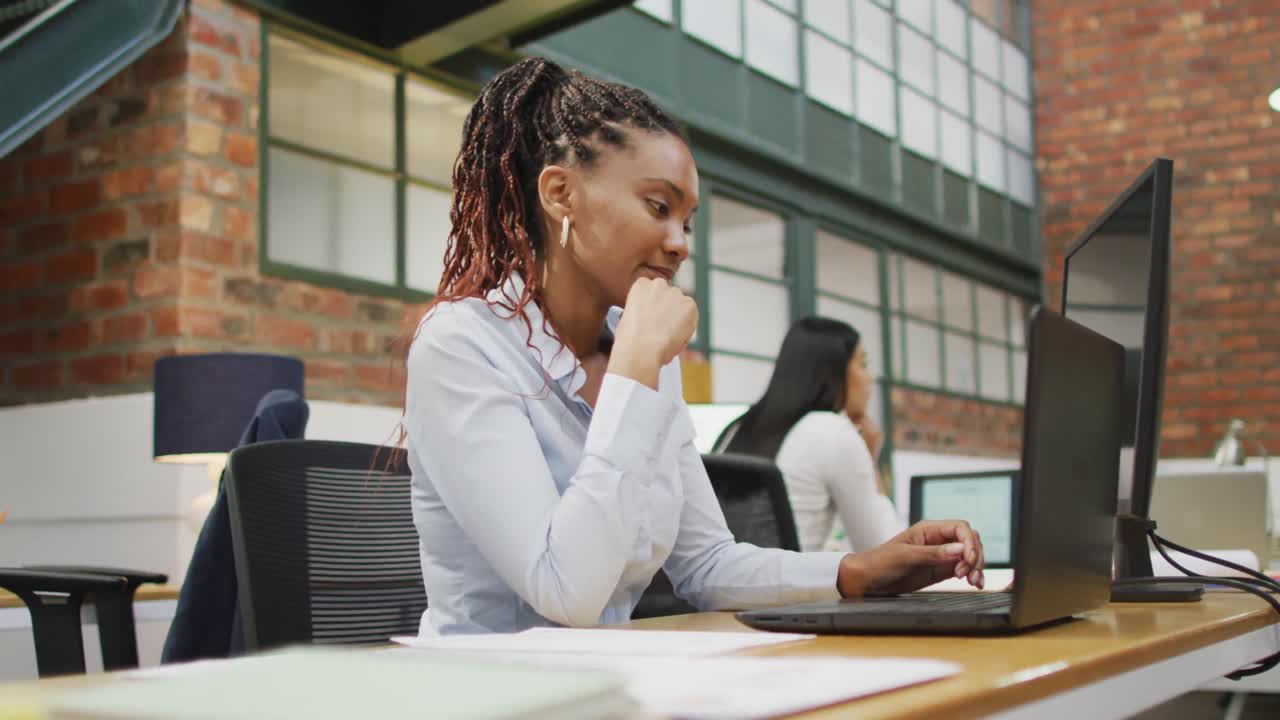 Happy african american businesswoman using laptop at office