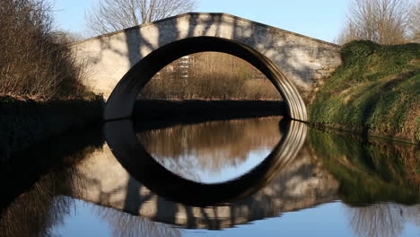 stone arch bridge reflected in calm water