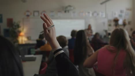 student raises hand during class discussion to ask question in high school