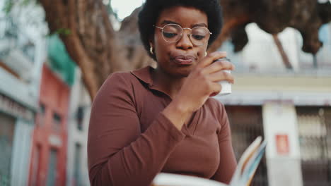 estudiante de piel oscura con un libro tomando un café al aire libre