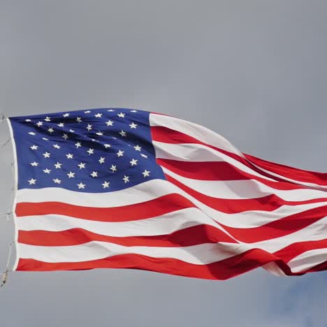 Große-US-Flagge-Auf-Einem-Hintergrund-Von-Grauem-Himmel,-Wunderschön-Von-Der-Sonne-Beleuchtet