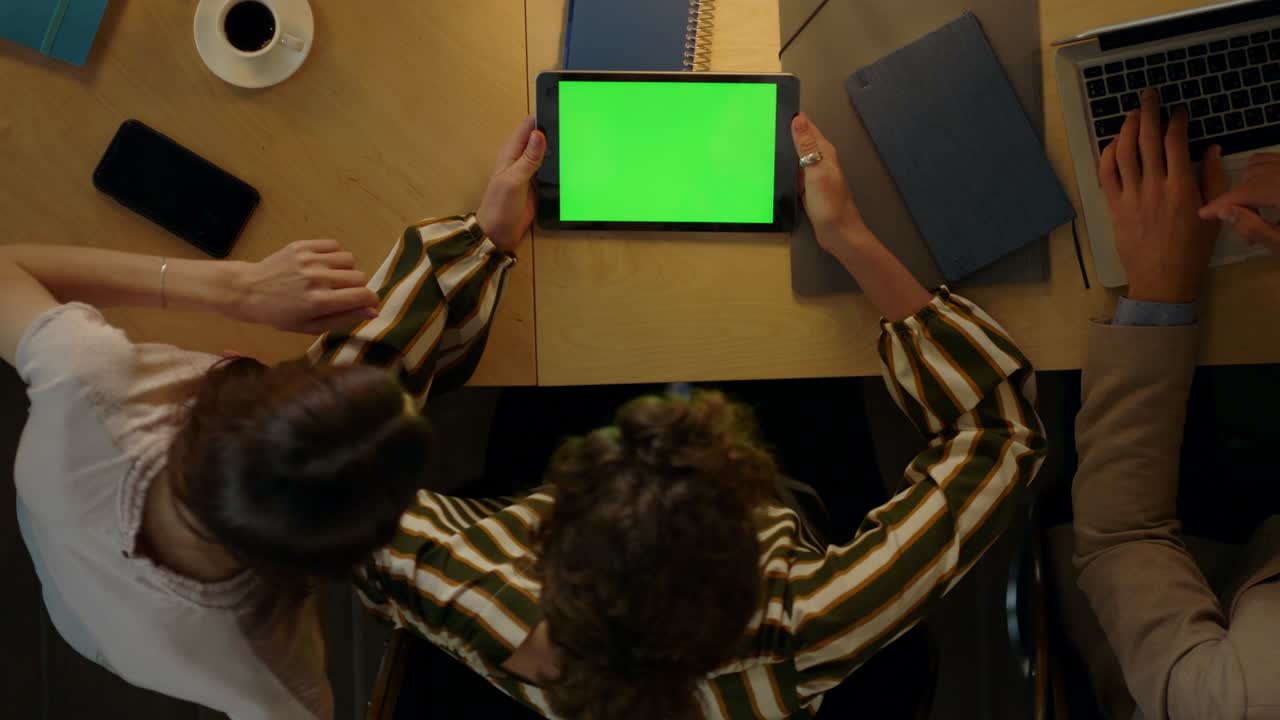 Woman showing project to colleagues on green screen device. Team using tablet.