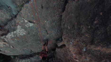 climbing sportswoman rappelling down the mountain