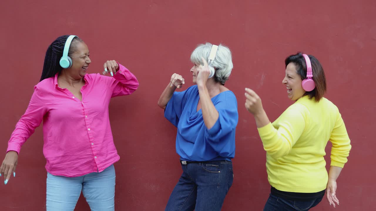 Multiracial senior woman dancing and listening music together outdoor - Elderly lifestyle concept