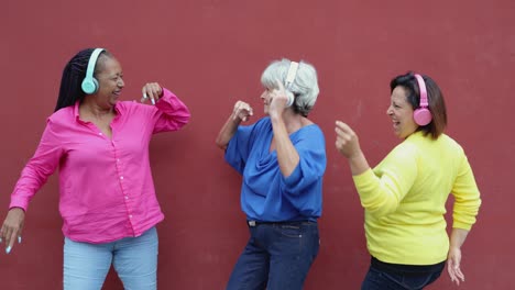 multiracial senior woman dancing and listening music together outdoor - elderly lifestyle concept