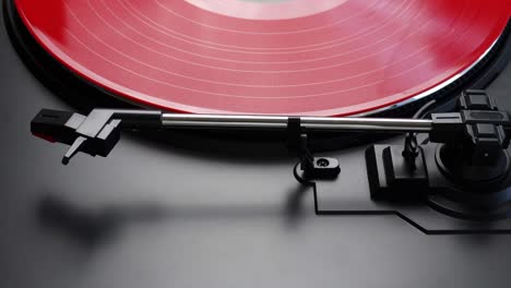 placing red vinyl record on a turntable. spinning red lp on a turntable. proces of preparing album for listening on a gramophone