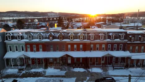 golden sunrise over a row of historic townhouses covered in snow, captured from above by a drone in the usa