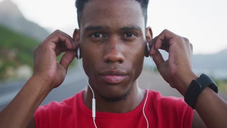 portrait of african american man wearing earphones while standing on the road