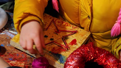 children, during practical christmas workshops, hammer nails into shapes and create decorations with yarn and board