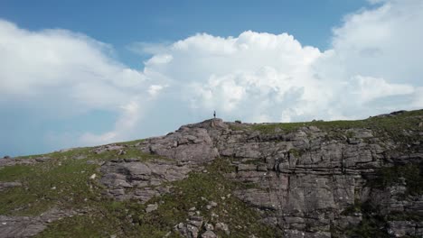 un excursionista de pie en el lado de una montaña con nubes tormentosas detrás de él en las tierras altas escocesas