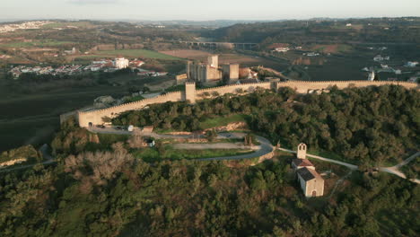 vista panorámica de la ciudad medieval y el castillo rodeados de un exuberante follaje verde en obidos, portugal