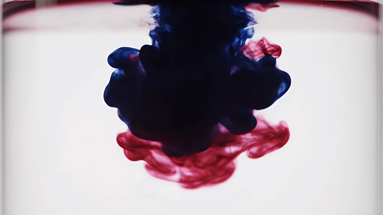 Goccioline di inchiostro rosso e blu che si mescolano in acqua limpida
