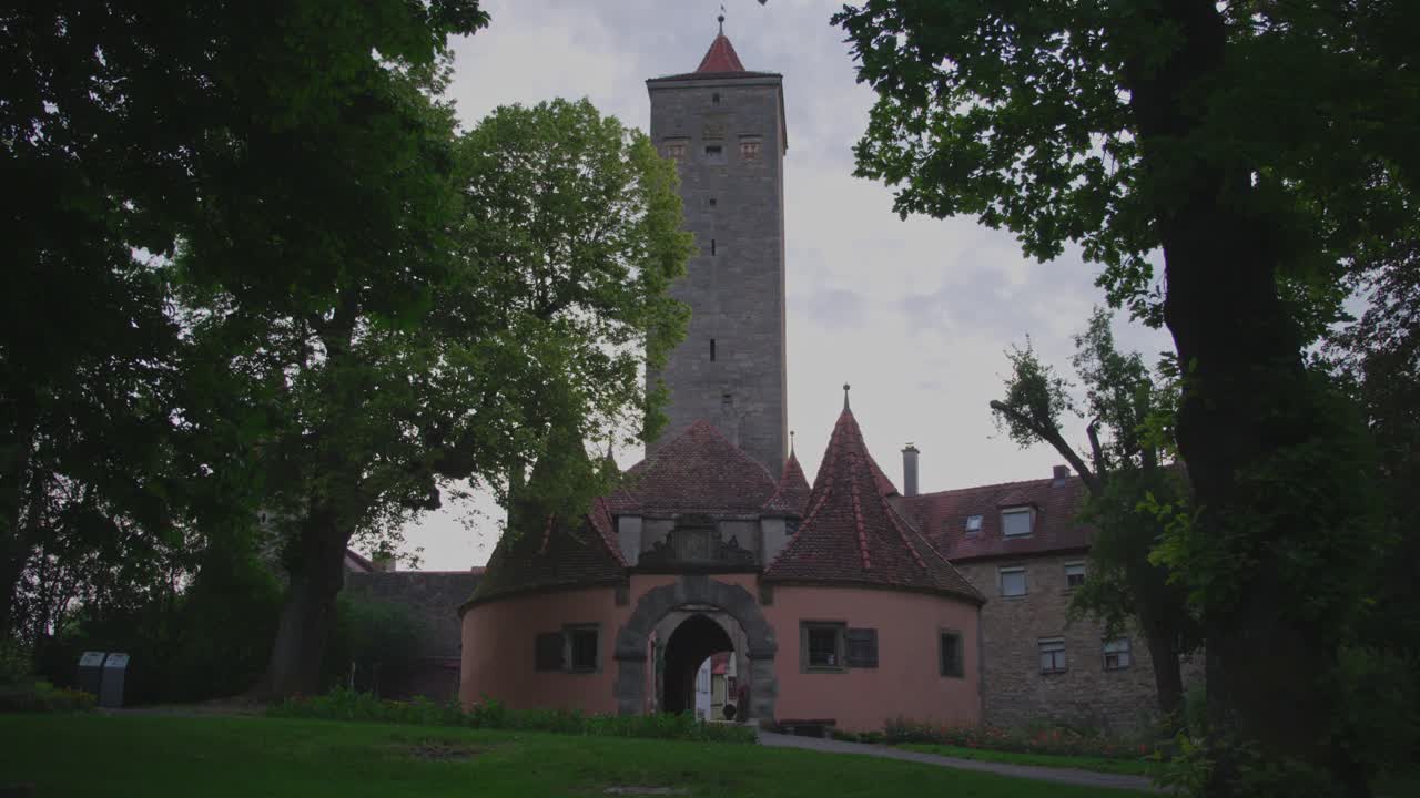 The iconic Burgtor gate of Rothenburg ob der Tauber stands prominently amidst lush trees, showcasing its historic architecture and cultural significance in a picturesque setting.