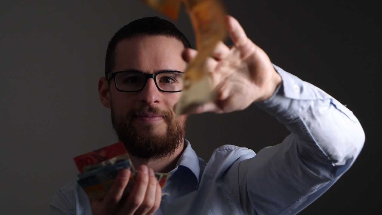 Homem rico e bem-sucedido financeiramente jogando dinheiro para o alto, em câmera lenta