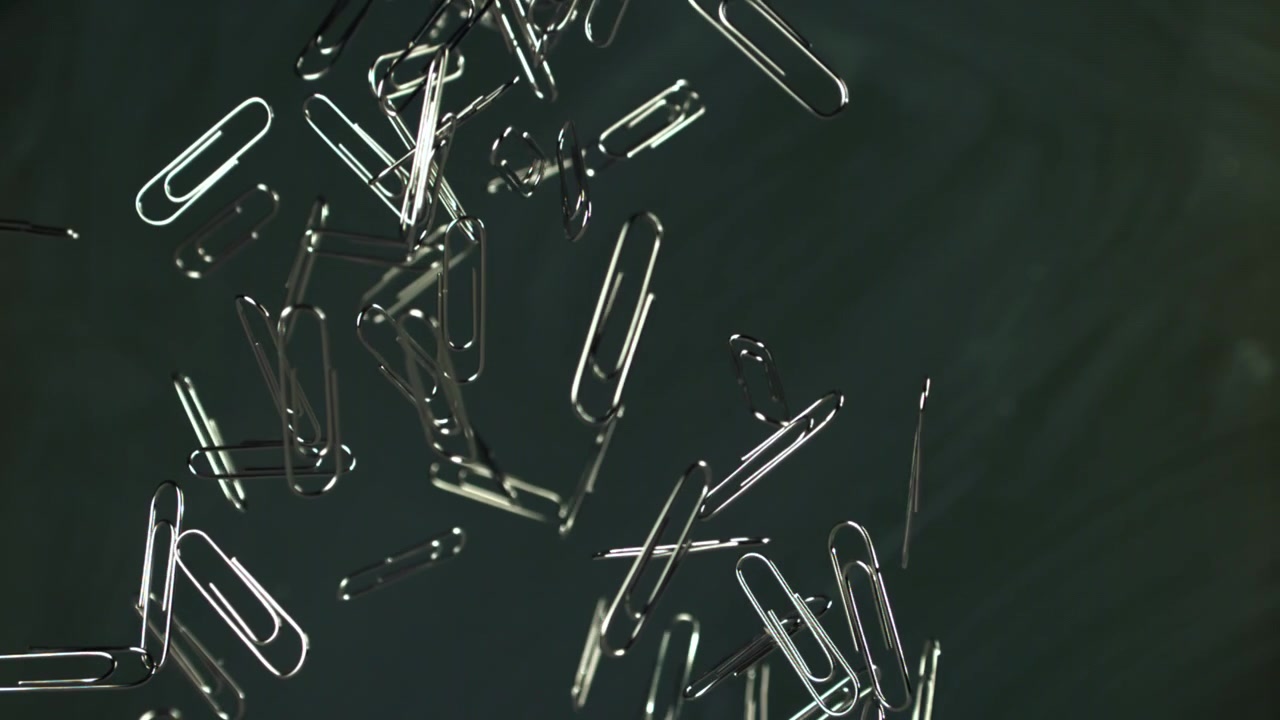 Slow Motion of Paper Clips Falling on Dark Background