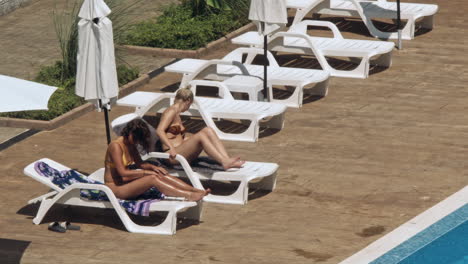 beautiful young women relaxing on the deck chair near the pool